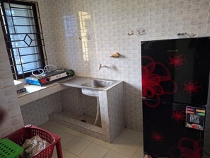 Una cocina con un lavabo, una ventana con reja metálica, un refrigerador y una encimera con varios objetos.