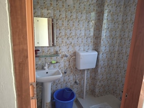 Un baño con un lavamanos blanco, un inodoro y un balde azul.