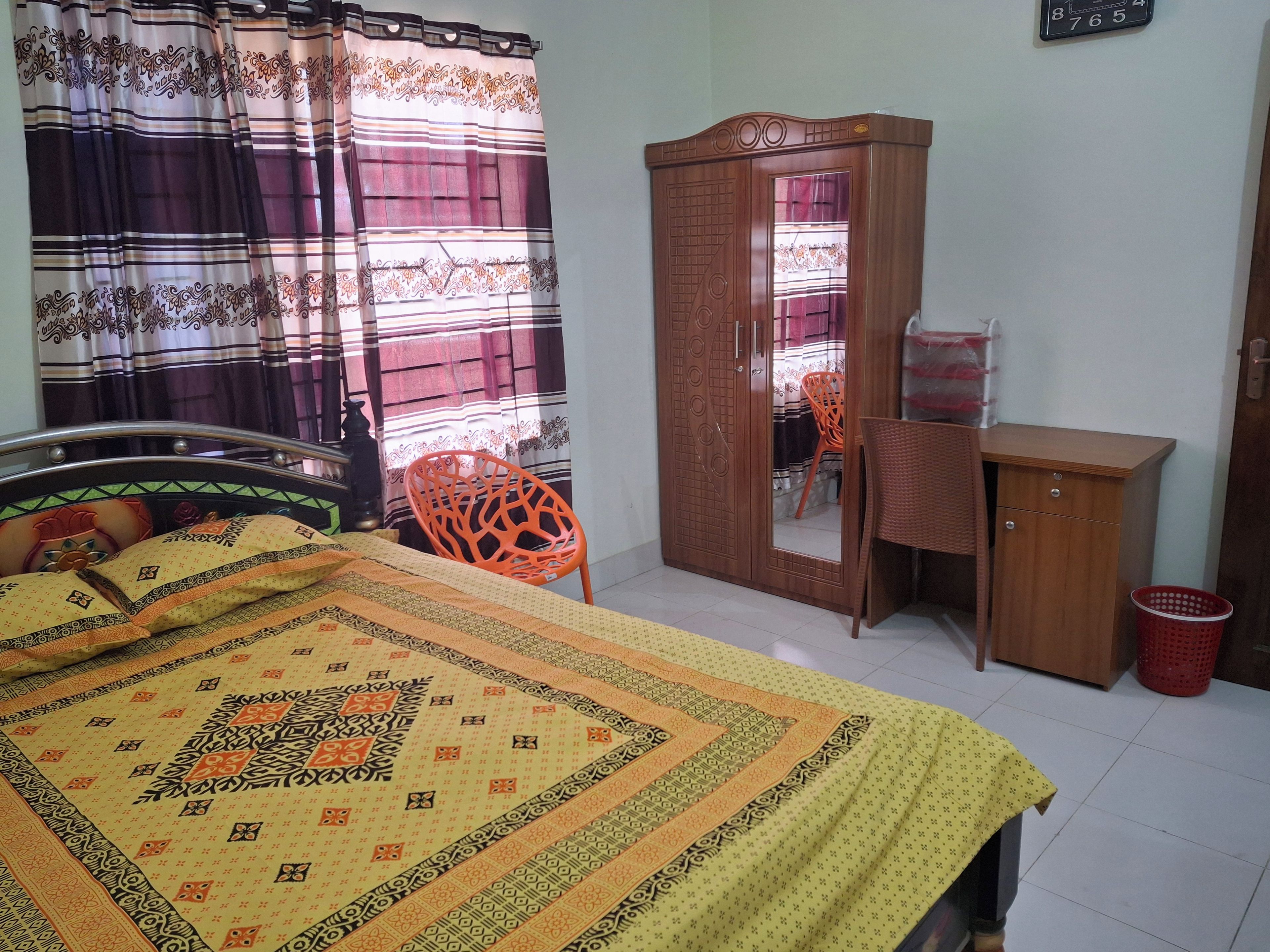 Quarto com cama, guarda-roupa de madeira, escrivaninha e cadeira.
