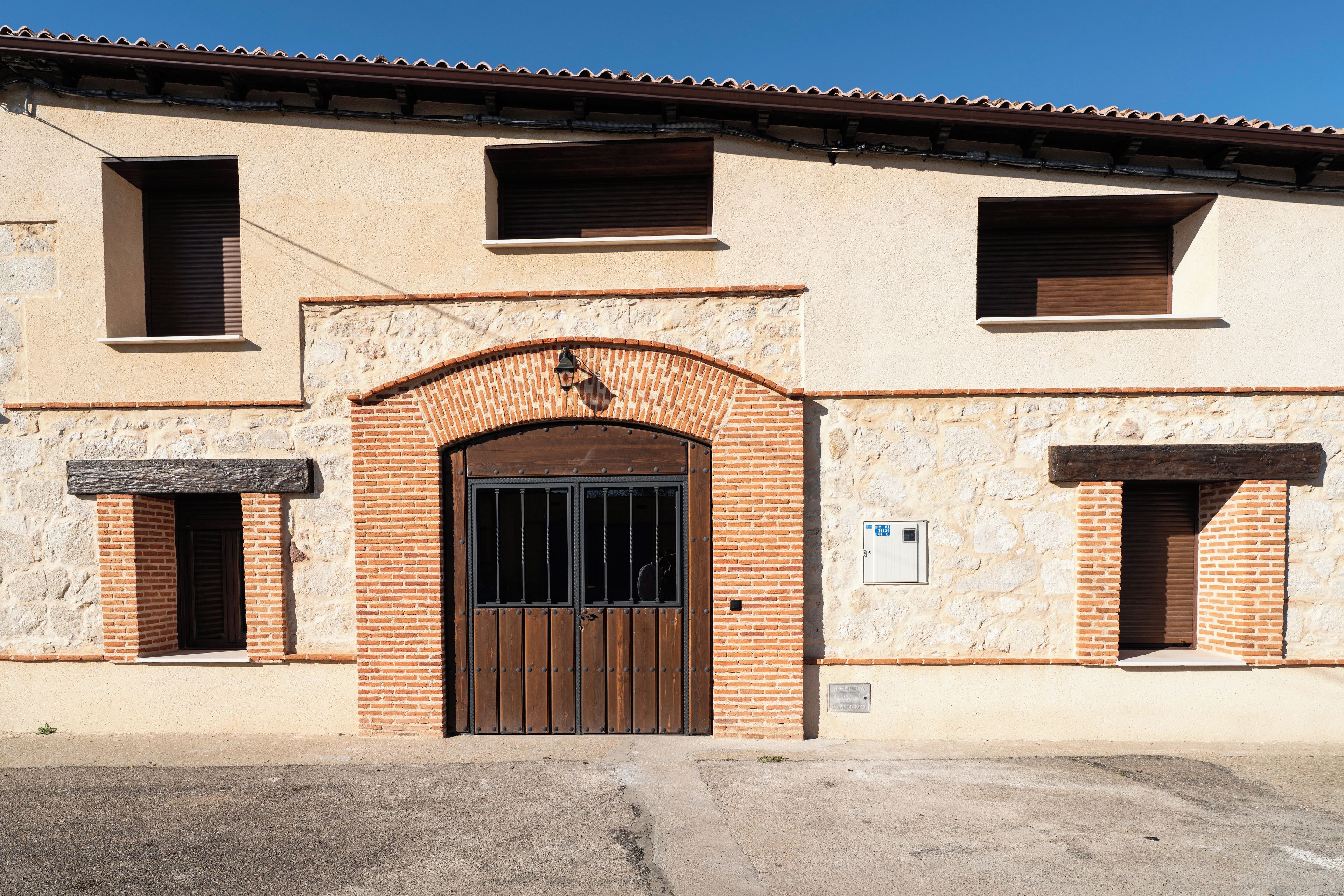 A building with a central arched entrance, two side windows, and a tiled roof.