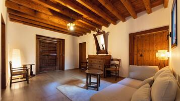 Una habitación con vigas de madera en el techo, una puerta grande de madera, un aparador, un espejo y un sofá.