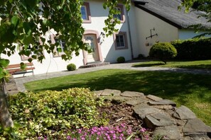 Ein Gebäude mit weißer Fassade, einem geneigten Dach und einem steinernen Weg, der zum Eingang führt.