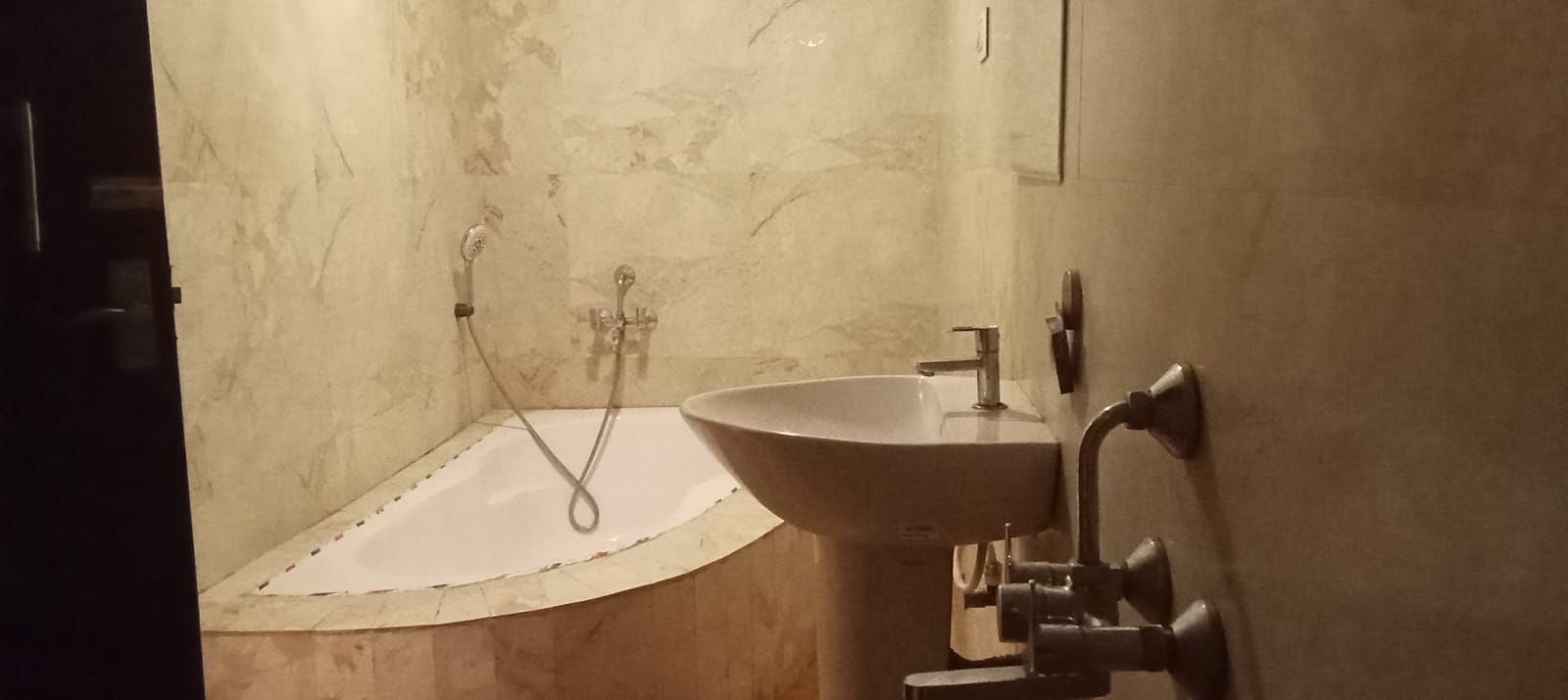 Ein Badezimmer mit Waschbecken, Dusche und Marmorwand.