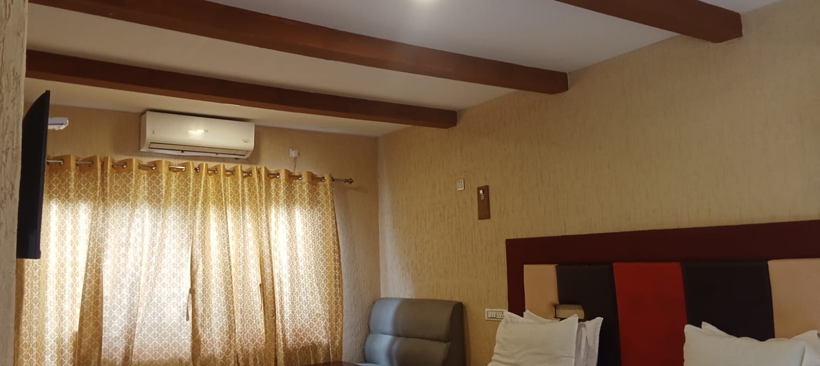 Ein Hotelzimmer mit einem Bett, einem Sessel, einem Vorhang und einer Klimaanlage.