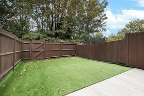 A fenced backyard with artificial grass and a wooden deck. - Stylish 3-Bed | Ebbsfleet & Bluewater | Parking (Northfleet)