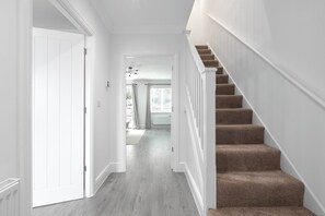 A hallway with a carpeted staircase and a door leading to another room. - Stylish 3-Bed | Ebbsfleet & Bluewater | Parking (Northfleet)