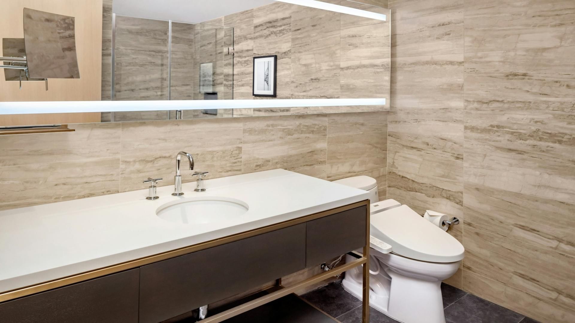 Un baño moderno con un lavabo blanco, un inodoro y un espejo grande.
