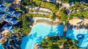 An aerial view of a resort with a large swimming pool, lounge areas, and palm trees. - Big Island Ocean Tower Stay with Partial Ocean View, Pools & Waikoloa Resort Fun (Waikoloa Village)