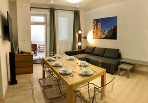 A modern living room with a dining area, a sofa, a TV, and a painting on the wall. - Spacious 1-bedroom apartment in Prague Old Town (Prague)