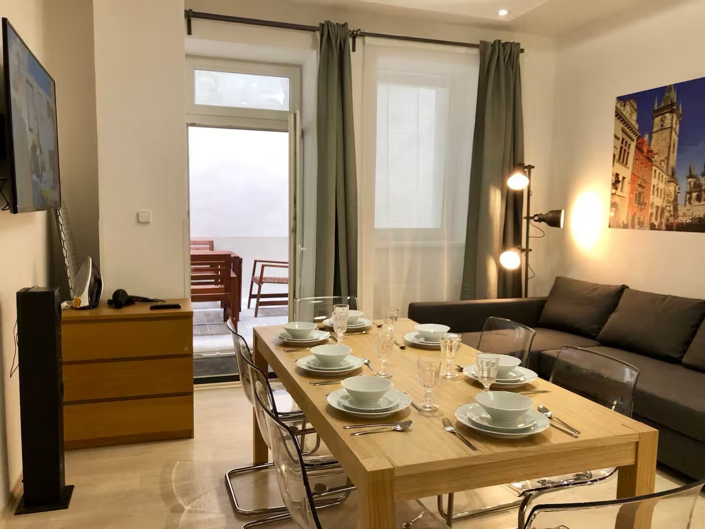 Un coin repas avec une table dressée pour quatre personnes, un canapé et un téléviseur posé sur un meuble.