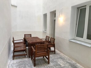 A patio with a wooden table and chairs, a window with a view, and a light fixture. - Spacious 1-bedroom apartment in Prague Old Town (Prague)