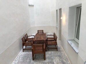 A covered patio area with a wooden table and chairs, a window with a view, and a wall-mounted light fixture. - Spacious 1-bedroom apartment in Prague Old Town (Prague)