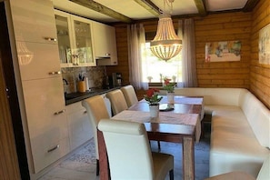 A cozy dining area with a wooden table, white chairs, and a bench. - by the lake with lake and Bavarian Forest views (upper floor) (Arrach\/ Kummersdorf)