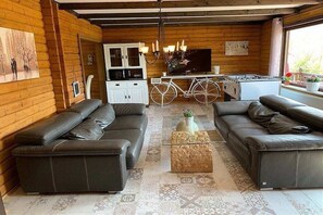 A log cabin interior with leather sofas, a dining area, and a bicycle. - by the lake with lake and Bavarian Forest views (upper floor) (Arrach\/ Kummersdorf)