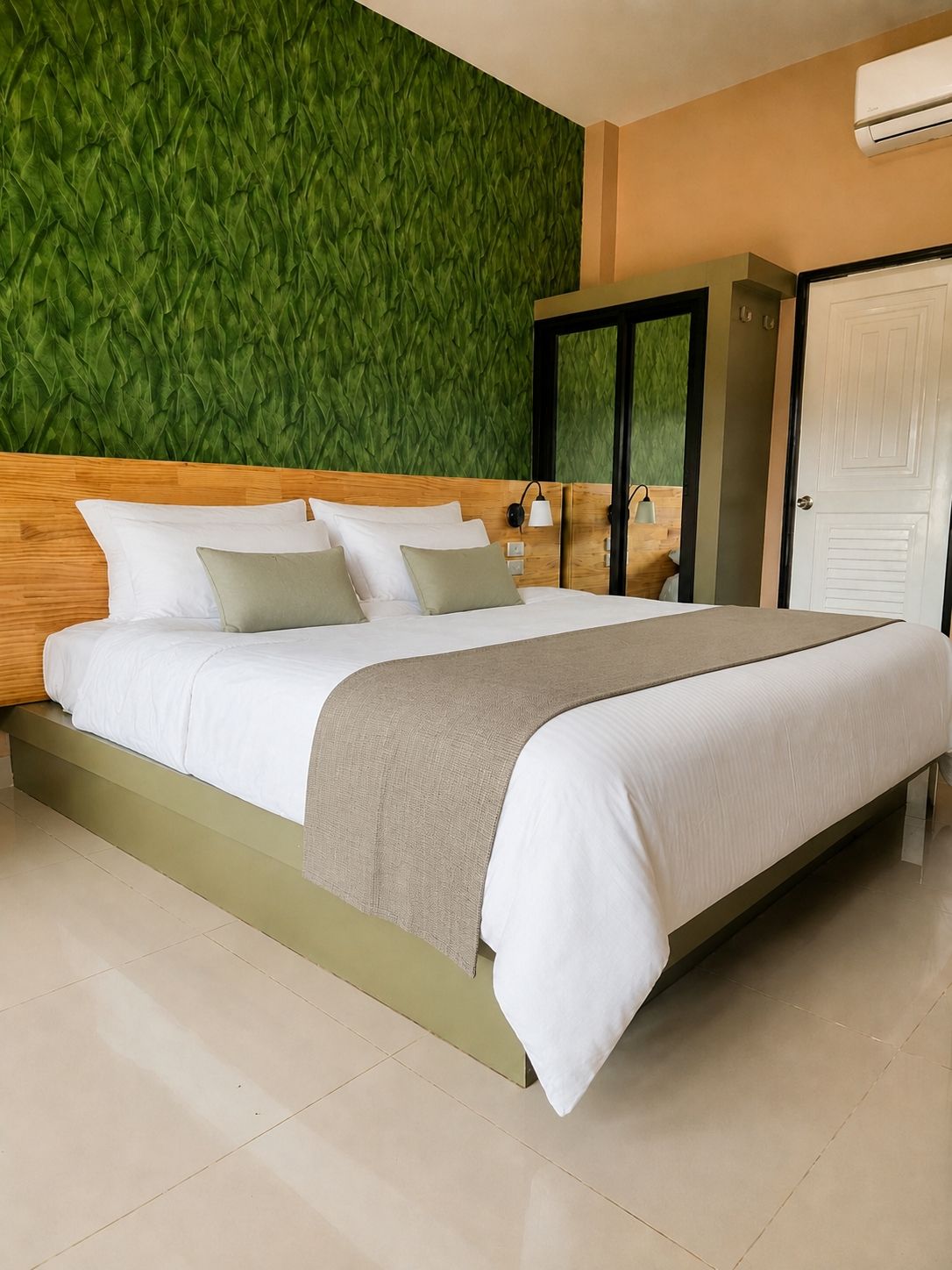 A modern hotel room with a large bed, a green textured wall, and a white door.