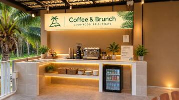 Estación de café y brunch con un letrero, una máquina de café, un refrigerador para bebidas y una barra con varios artículos.