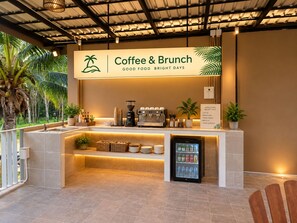 A coffee and brunch station with a sign, a coffee machine, a beverage cooler, and a counter with various items. - Flow Krabi resort (Mueang)