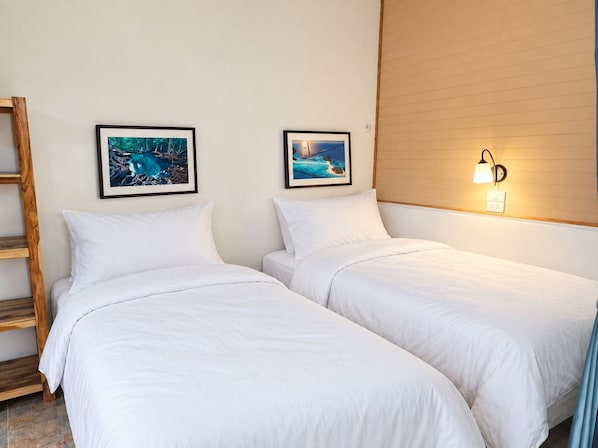 A hotel room with two single beds, a wooden ladder, and two framed pictures on the wall. - Flow Krabi resort (Mueang)