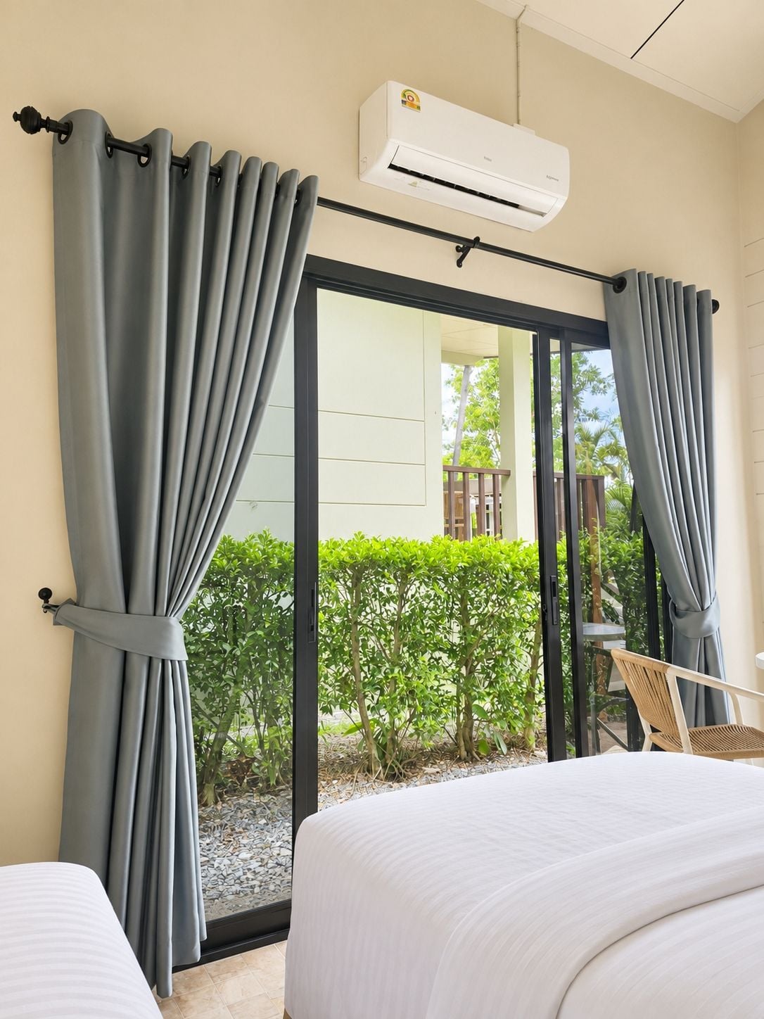 A hotel room with a bed, a chair, and a view of a garden through a glass door.