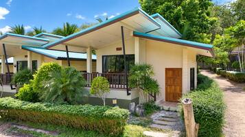 A hotel with a covered outdoor area, a wooden door, and a paved walkway.