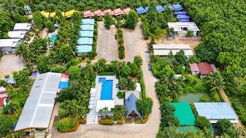 An aerial view of a resort with multiple buildings, a swimming pool, and lush greenery.