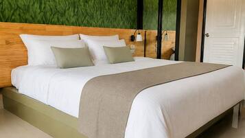 A modern hotel room with a large bed, a green textured wall, and a white door.