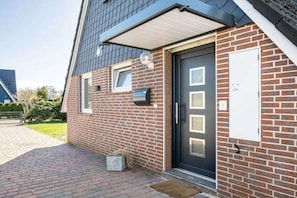 Ein Ziegelhaus mit einer schwarzen Tür, einem kleinen Fenster und einem Briefkasten an der Seite.