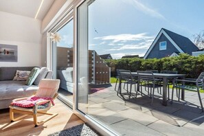 Ein modernes Wohnzimmer mit Glastür, die zu einer Außenpatio führt.