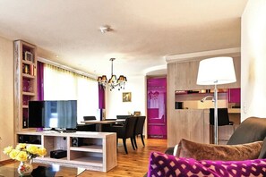 Ein modernes Wohnzimmer mit Flachbildfernseher, Essbereich und Küchenzeile.