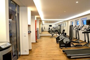 Ein Fitnessstudio mit Cardiogeräten und Gewichten, Holzboden und einer Glaswand.