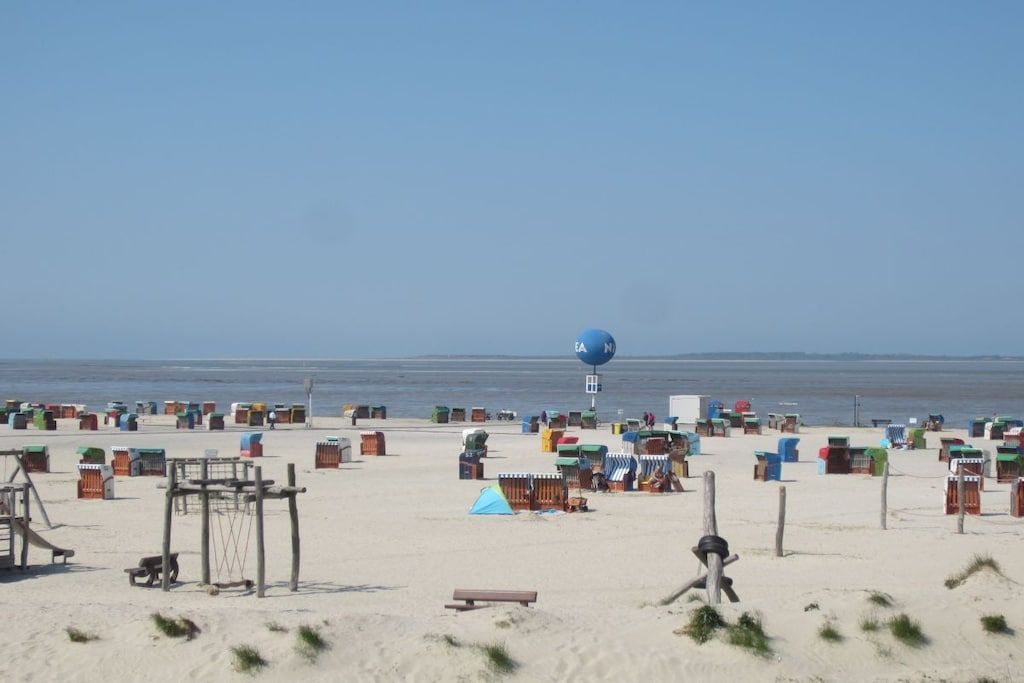 Uma praia com várias cabanas coloridas e uma grande estrutura em forma de bola azul.