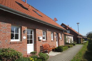 Ein Backsteinhaus mit rotem Ziegeldach, einer Bank und einem Weg zum Eingang.