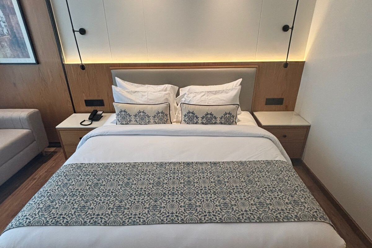 Een moderne hotelkamer met een groot bed, twee nachtkastjes, een nachtkast en een wandlamp.