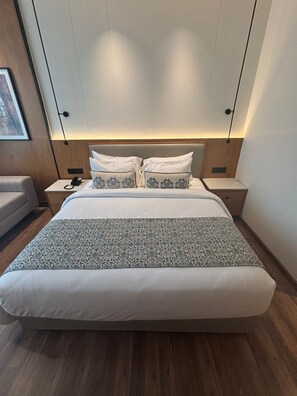 Een moderne hotelkamer met een groot bed, twee nachtkastjes, een nachtkast en een wandlamp.