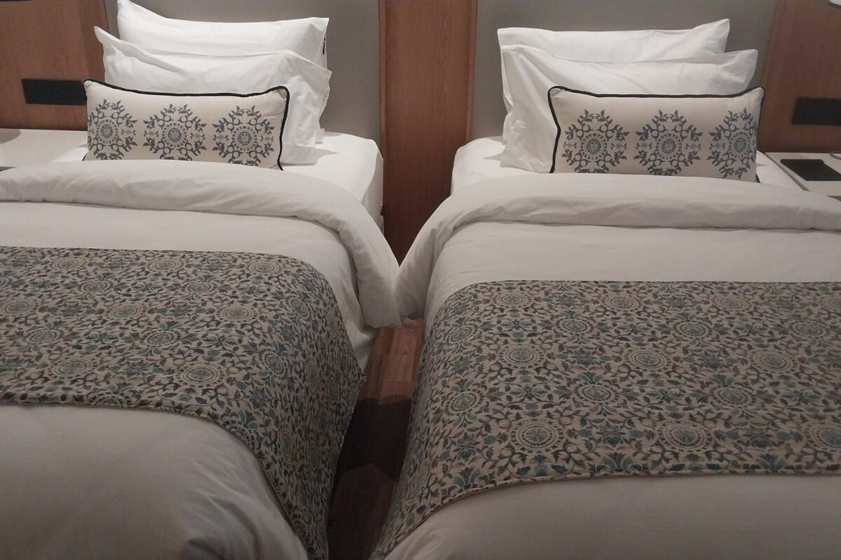 Een tweepersoonsbed met een bedovertrek met patroon en twee sierkussens met bloemenprint.