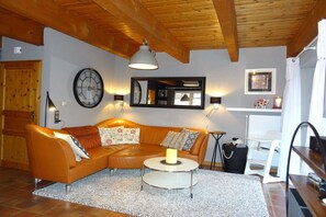 A cozy living room with a leather sofa, a round coffee table, a wall clock, and a ceiling lamp. - Holiday home in Hooksiel with swimming pool (Hooksiel)