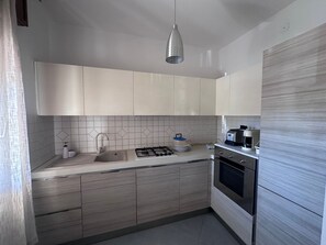 A modern kitchen with a gas stove, sink, and stainless steel appliances. - Holiday Home 'Angel’s House' (San Giovanni Suergiu)
