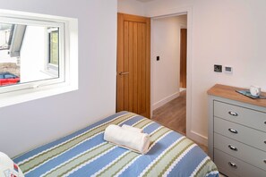 Un dormitorio con cama, puerta de madera, cómoda y ventana.