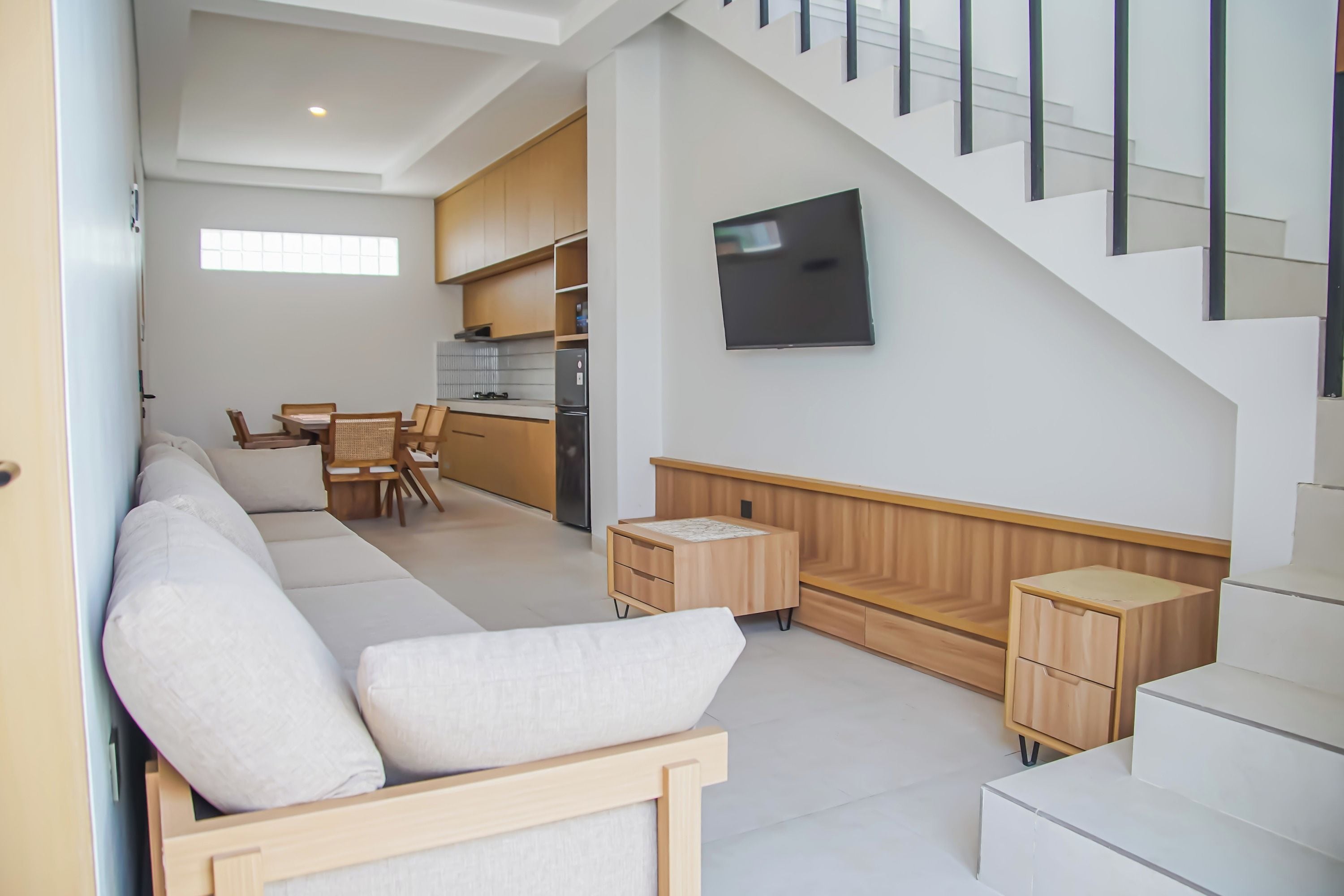 A modern living room with a sofa, a dining area, and a kitchen in the background.