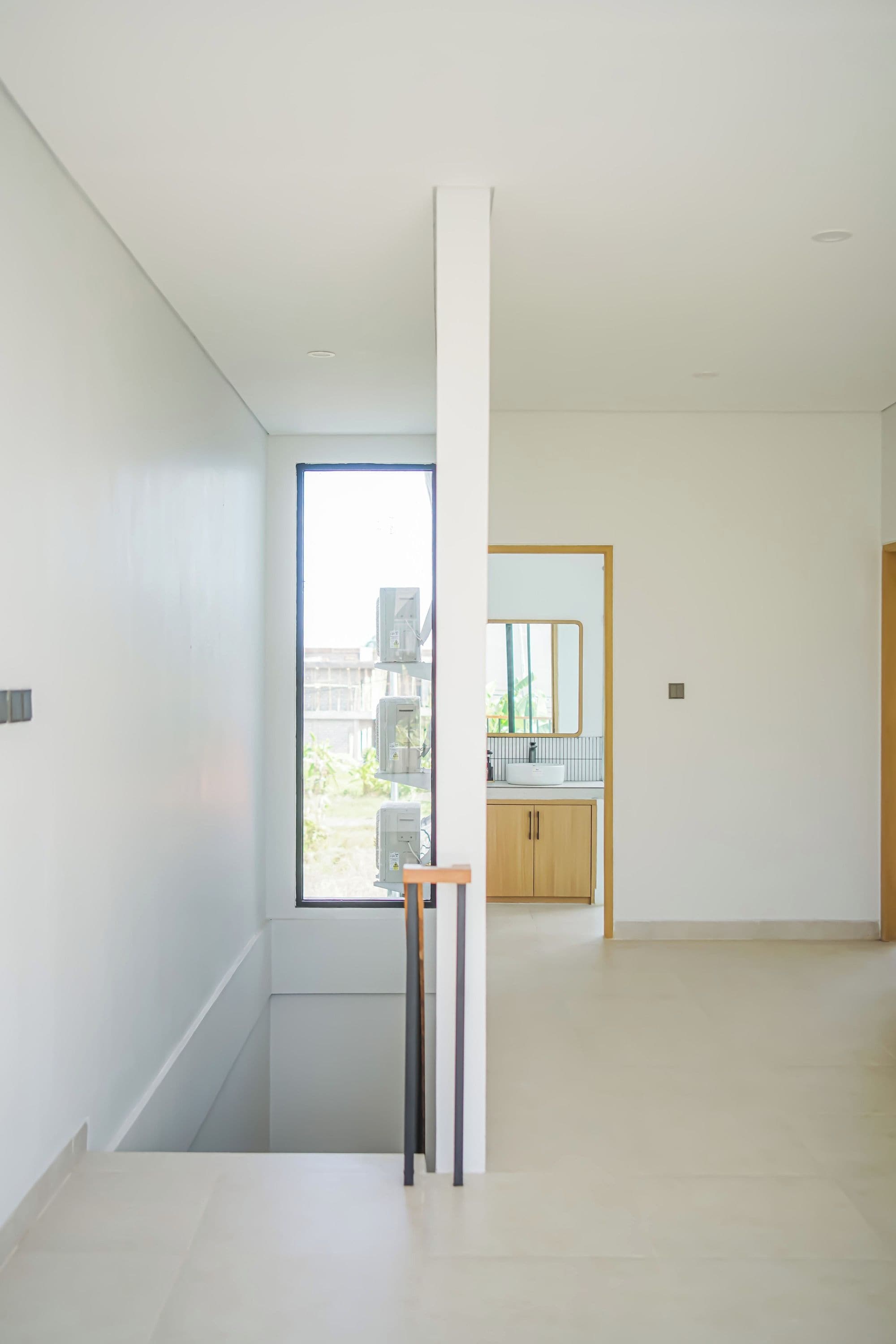 A modern interior with a large window, a staircase, and a minimalist bathroom.