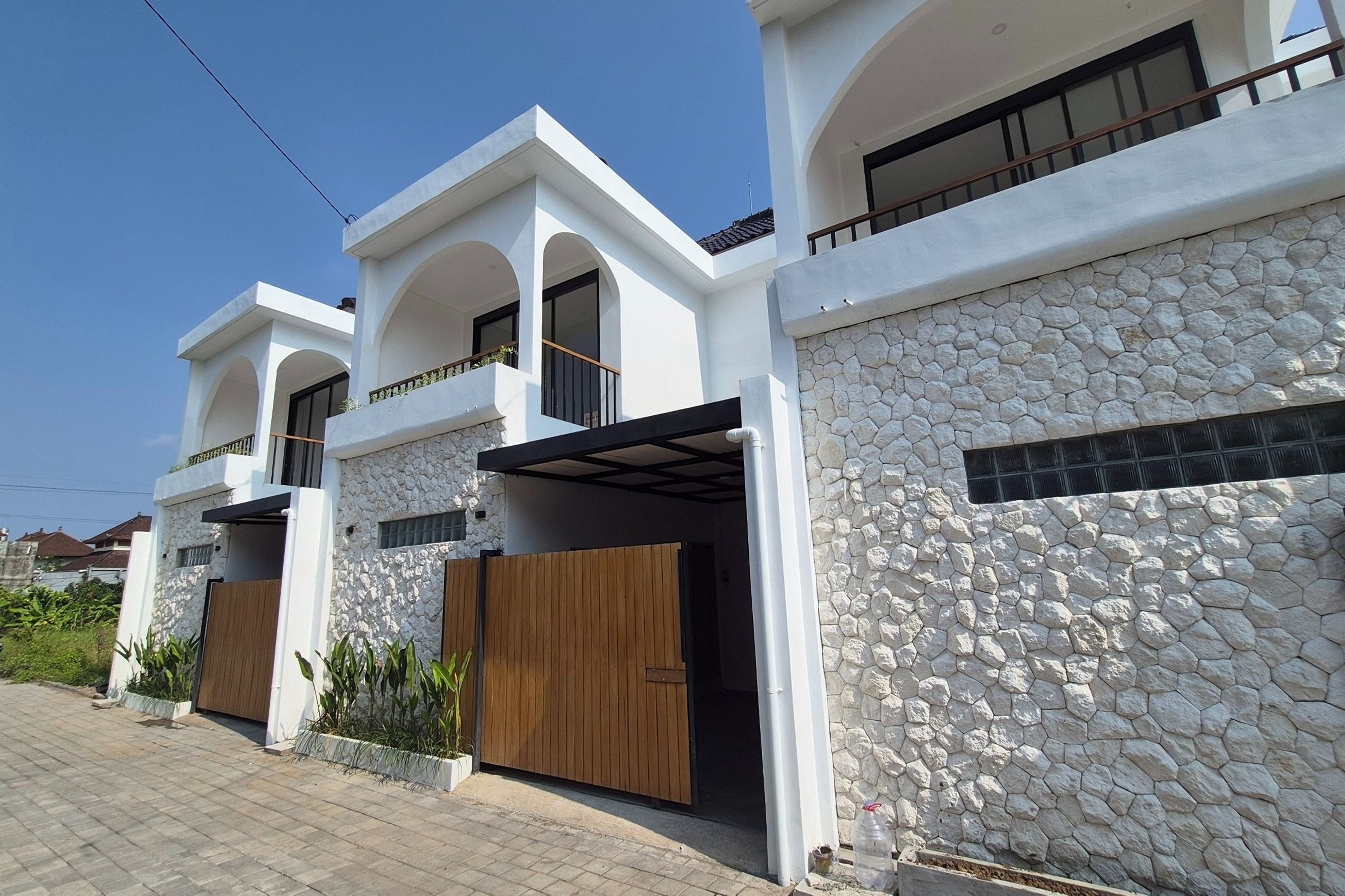 A modern two-story house with a stone facade and wooden doors.