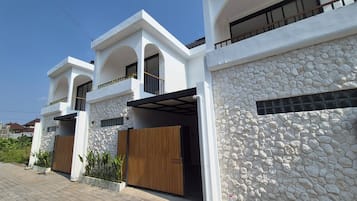 Una casa moderna de dos pisos con fachada de piedra y puertas de madera.