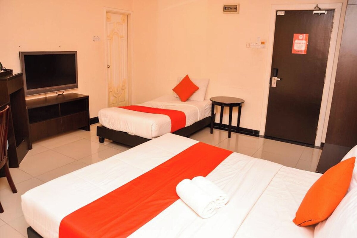 A hotel room with two beds, a TV, a small table, and a door.