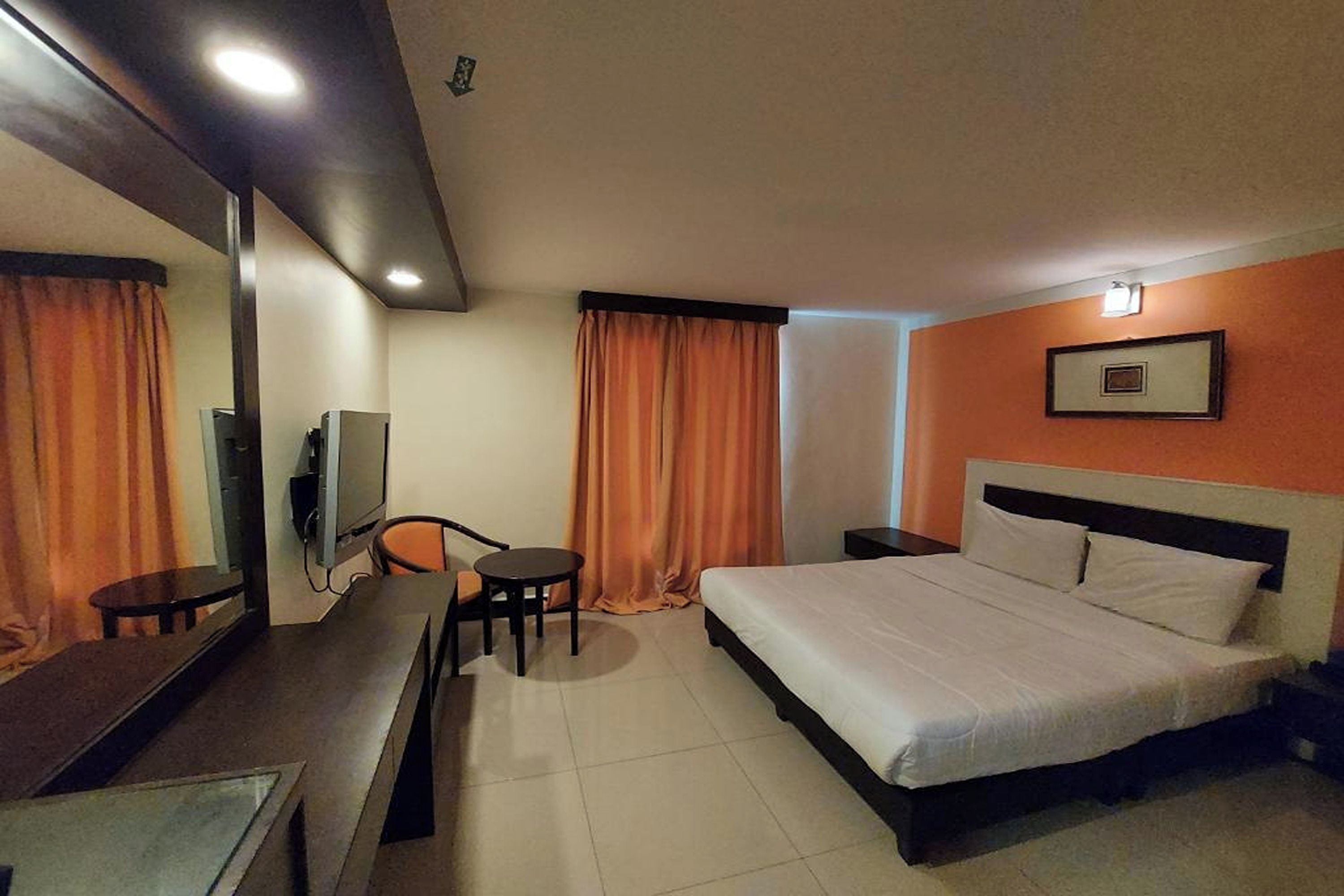 A hotel room with a bed, a desk, a chair, a television, and a picture on the wall.