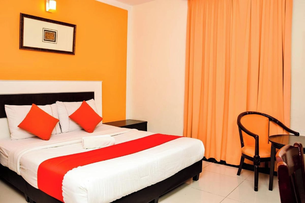 A hotel room with a bed, a nightstand, a chair, and a table.