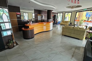 A reception area with a curved counter, a sofa, and a coffee table. - Hotel Sahara Rawang (Rawang)