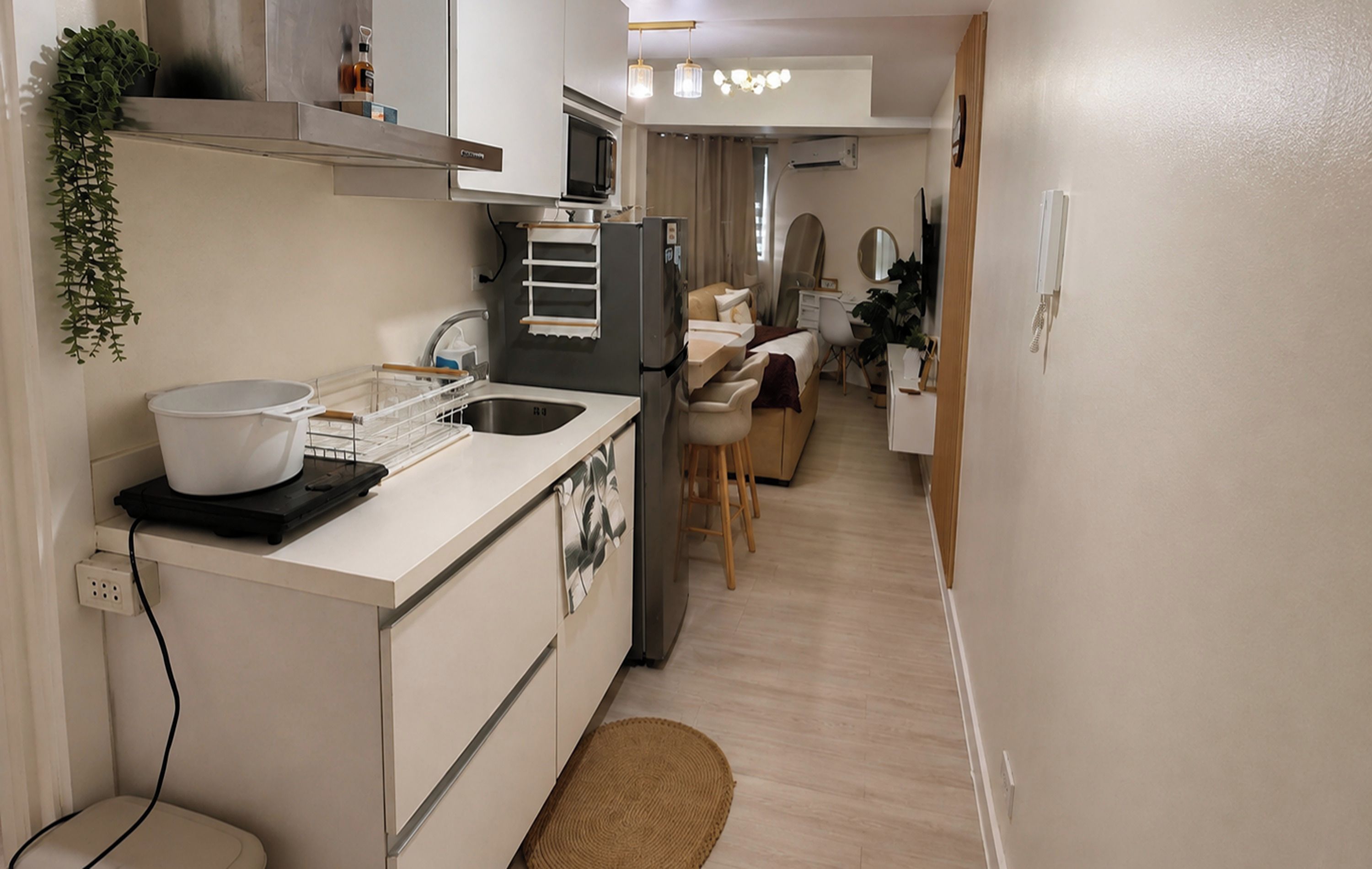 Cocina compacta con un lavamanos, un microondas y un refrigerador pequeño. Hay un comedor con una silla y una mesa.