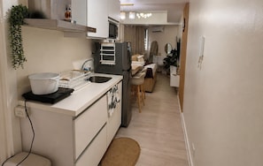 A compact kitchen with a sink, a microwave, and a small refrigerator. There is a dining area with a chair and a table. - Azure Urban Resort Residences Parañaque (Paranaque)