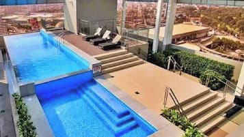 A rooftop pool with a view of the city, steps leading down to the pool, and lounge chairs.