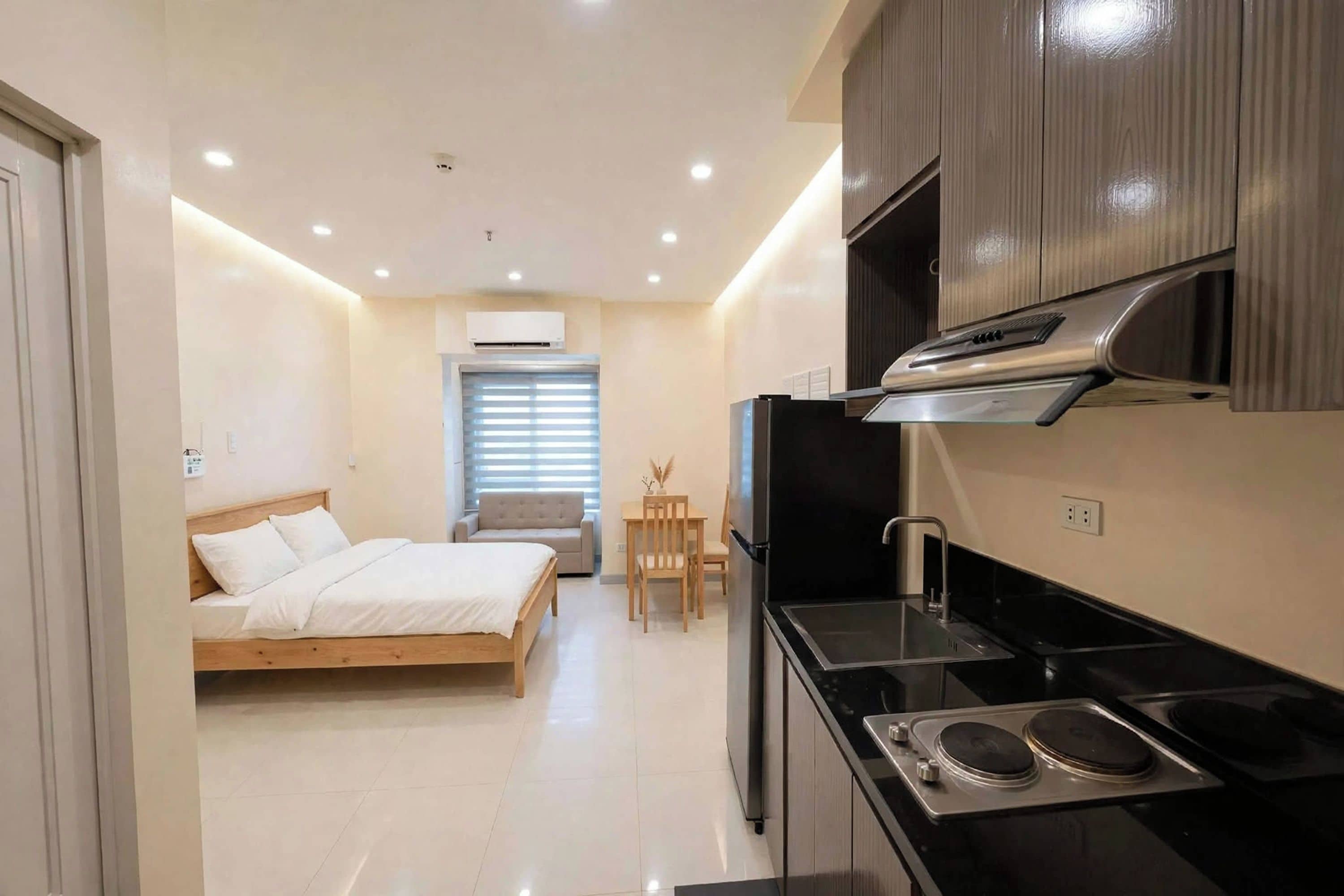A compact hotel room with a bed, kitchenette, and a small dining area.